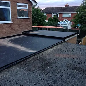 A flatbed trailer is parked in front of a house.